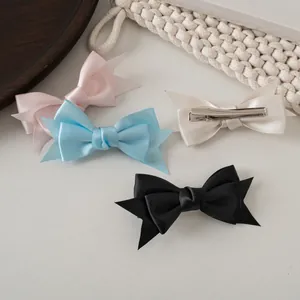 Détail de barrettes à double nœud en satin crème avec pinces crocodile en acier inoxydable