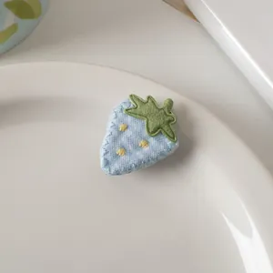 Dettaglio macro della clip per capelli a fragola in tessuto blu a pois ricamati