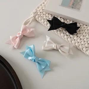 Détail de quatre barrettes à cheveux en ruban de satin coloré sur fond en tricot blanc