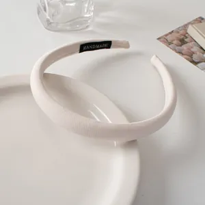 Detail of white padded sponge headband with HANDMADE label on fabric texture
