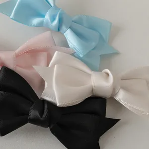 Quatre sets de barrettes à double nœud en satin en couleurs crème, bleu, rose et noir