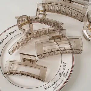 Transparent smoke gray hair claws in large size displayed on an elegant white ceramic dish