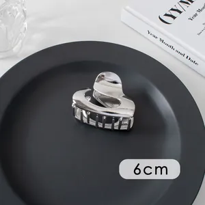Detailed view of a 6cm silver heart-shaped metal hair claw clip on a black tray
