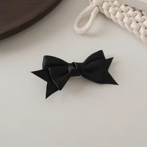 Détail d'une barrette à cheveux nœud en satin noir double couche avec bords en queue d'aronde