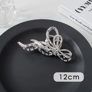 Detail of 12cm silver metal hair claw with ribbon design and central pearl accent