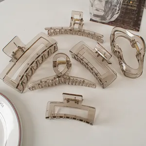Detail of six transparent smoky grey hair claws in various geometric designs on a white desk