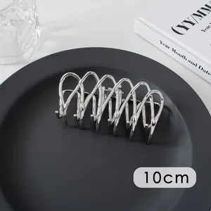 Detail view of 10cm silver metal hair claw clip with a sleek wavy line design on a black plate