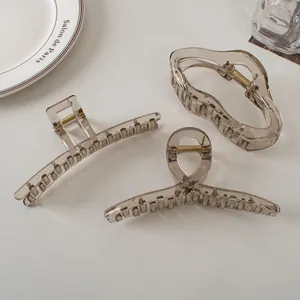 Detailed set of three translucent grey claw clips with elegant golden metal springs