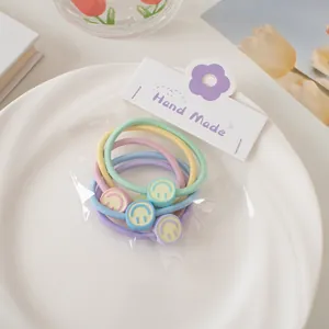 Gros plan de quatre élastiques à cheveux macaron avec des breloques smiley sur une carte