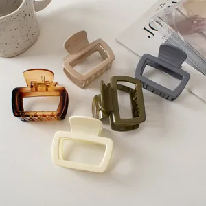 Collection of small square hollow hair claws in minimalist earth tones on white desk
