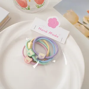 Détail d'élastiques à cheveux macaron avec breloques d'ours dans un décor élégant