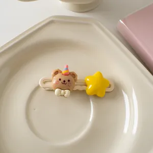 Gros plan d'une barrette ours mignonne avec étoile jaune et nœud sur un plateau en céramique