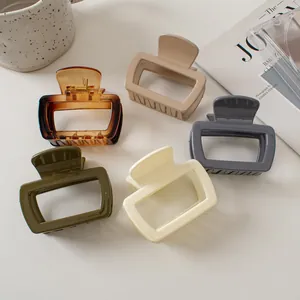 Flat lay of five rectangular hair claws in amber, cream, and olive on a stylish magazine