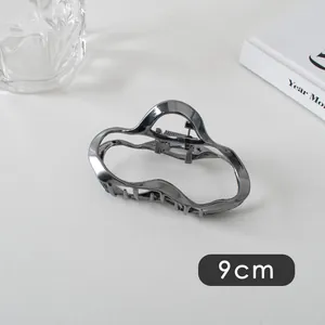 Detail of a 9cm wave-shaped gunmetal silver hair claw clip with metallic finish
