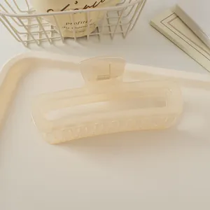 Détail d'une pince à cheveux carrée mate de couleur crème avec ressort métallique
