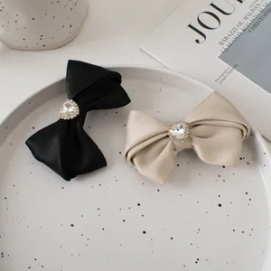 Detail of satin bow hair clips with heart rhinestone on ceramic tray and magazine