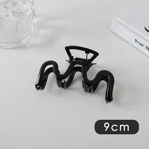 Detail view of 9cm large matte black wavy hair claw clip for elegant bun hairstyles