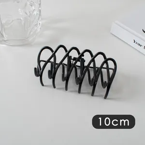 Detailed view of a 10cm black metal wave hair claw clip with cross design on grey surface