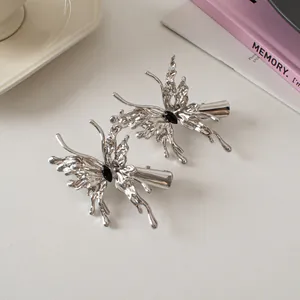Close-up of silver liquid metal butterfly hair clips with black center gemstone detail