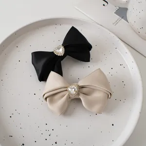 Detail of satin bow hair clips with heart rhinestones on a white ceramic tray