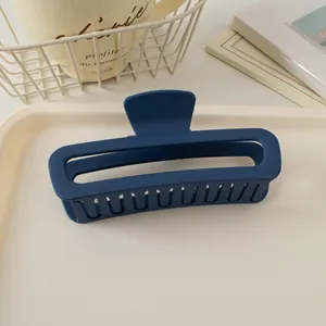 Détail d'une grande pince à cheveux rectangulaire bleu marine mat de 13cm sur un plateau