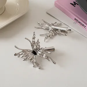 Silver liquid metal butterfly hair clips with black gemstone on soft cream background