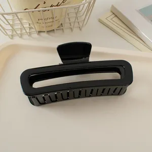 Pince à cheveux rectangulaire noire brillante sur un plateau blanc minimaliste