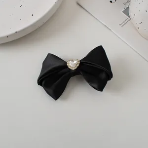 Detail of black satin bow hair clip with a sparkling heart rhinestone center ornament