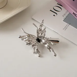 Silver liquid metal butterfly hair clip with black gemstone on a soft background