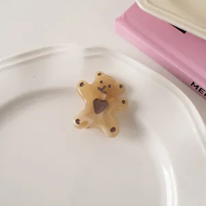 Macro view of cream bear hair clip with brown heart detail on a white ceramic plate