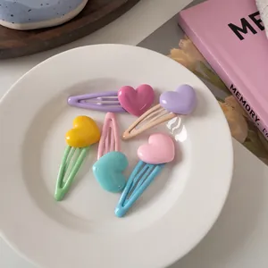 Dettaglio di fermagli per capelli colorati a forma di cuore su un piatto in ceramica bianca
