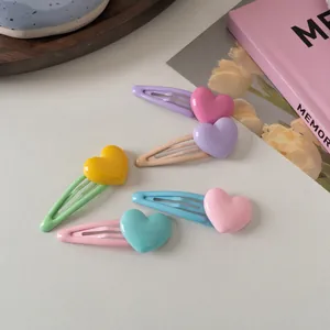 Set di fermagli per capelli colorati a forma di cuore su vassoio in legno e sfondo di libro