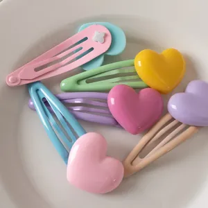 Set di 6 fermagli per capelli colorati a forma di cuore su piatto bianco
