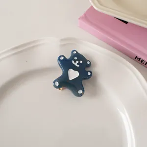 Detail of dark blue resin bear hair clip with heart detail on a white ceramic plate