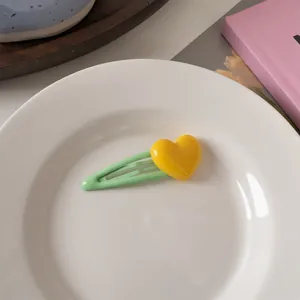Dettaglio del fermaglio per capelli a cuore macaron su un piatto di ceramica bianco