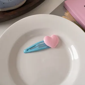 Primo piano di un fermaglio per capelli a cuore blu su un piatto bianco per uno stile dolce