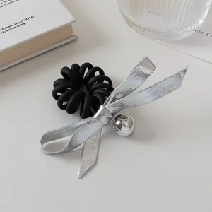 Détail d'un élastique spirale avec nœud argenté et pendentif sur un fond blanc