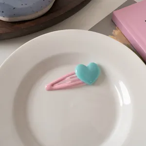 Dettaglio di un fermaglio per capelli rosa a forma di cuore su un vassoio di ceramica bianca