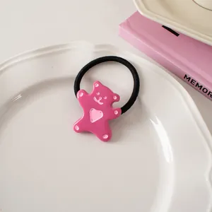Close-up of cute pink resin bear hair tie with heart detail on a white ceramic plate