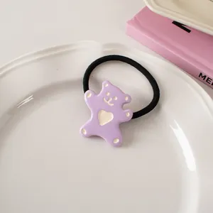 Detailed macro shot of a cute purple cartoon bear hair tie with heart on a white plate