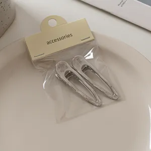 Detail von zwei Haarklammern aus gebürstetem Silber auf minimalistischer Displaykarte