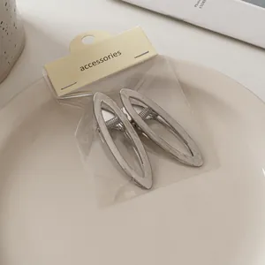 Detail von zwei gebürsteten silbernen Metall-Haarklammern mit hohlem ovalem Design