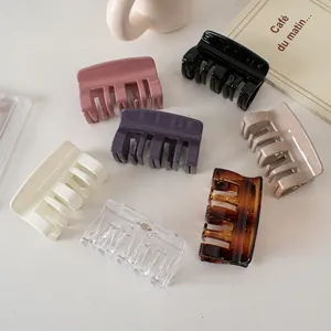 Set of seven glossy square hair claws in cream, pink, and amber on a minimalist desk