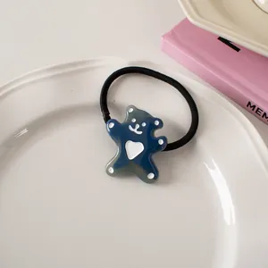 Detailed view of a cute blue bear hair tie with heart design on a white ceramic plate