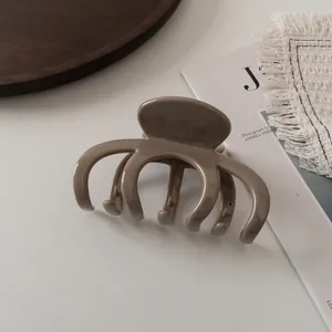 Große Haarklammer in glänzendem Khaki mit Mehrzahn-Design auf einem Marmortisch