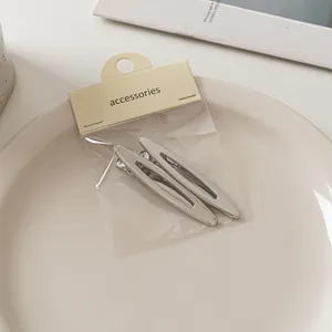 Detail von mattsilbernen Haarspangen aus Metall mit hohlem Oval-Design auf Keramiktablett