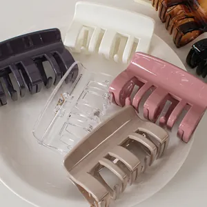 Glossy cream and colorful square hair claws set in a white ceramic dish for women