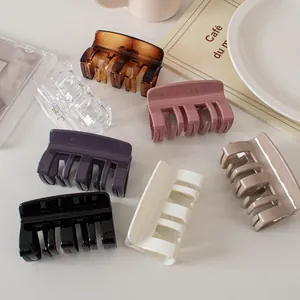 Close-up of gloss square hair claws in cream, black, and purple with wide teeth design