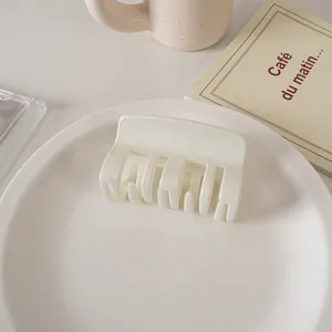Detail of a creamy white medium square hair claw clip placed on a white porcelain plate