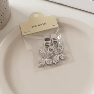Detailansicht der silbernen Schmetterlings-Haarspangen auf Keramikschale mit Karte